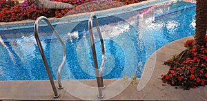 Two glasses of white vine stand by the swimming pool