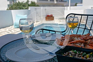 Two glasses of white wine and shrimps on the table by the pool