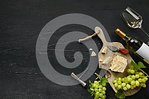 Two glasses of white wine and a tasty cheese plate on a wooden kitchen plate.