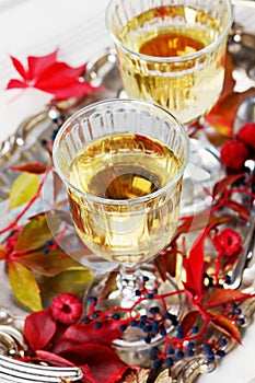 Two glasses of white wine on a vintage silver tray decorated with autumn grape, leaves and raspberries, romantic picnic