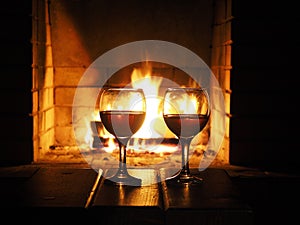 Two glasses of wine on the background of a burning fireplace. Concept winter evening together