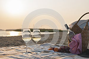 Two glasses of wine and a basket for a picnic. Romantic on the beach and sunset. Vacation. Free space for text. Copy space.