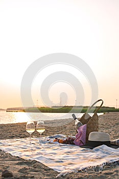 Two glasses of wine and a basket for a picnic. Romantic on the beach and sunset. Vacation. Free space for text. Copy space.