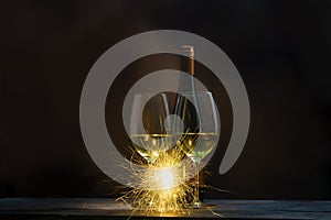 Two glasses of wine with bottles of wine decorated with incandescent fireworks