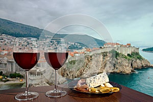 Two glasses of wine with charcuterie assortment against view of Dubrovnik, Croatia. Glass of red wine with different snacks -