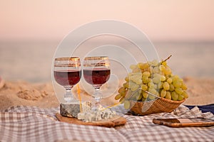 Two glasses of wine, cheese and fruits, close-up on the background of the sea.
