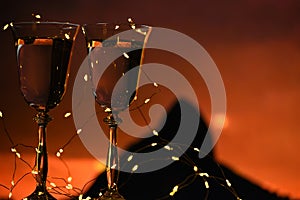 Two glasses of wine with garland lights on the background of night rocks.