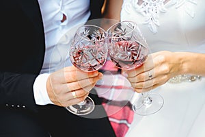 Two glasses of wine in the hands of newlyweds. Couple is clinking bocals.