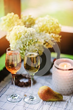 Two glasses of wine on summer table decorated with flowers.