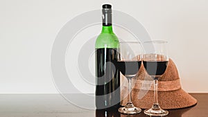 Two glasses of wine and wine bottle with hat on the wooden table