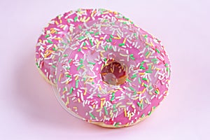 Two glazed pink donuts with icing on pink minimal background, top view