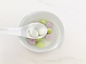 Two glutinous rice balls scooped up from a white bowl on a white spoon. top view.