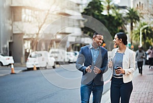 These two go-getters stay on the move. Shot of two businesspeople having a discussion while walking in the city.
