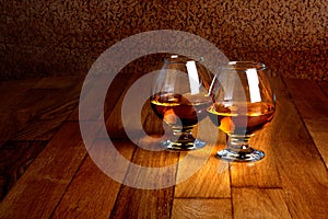 Two goblets of brandy on wooden counter top