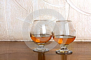 Two goblets of brandy on wooden counter top