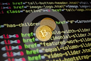 Two gold bitcoin coins on the background of lines of program code