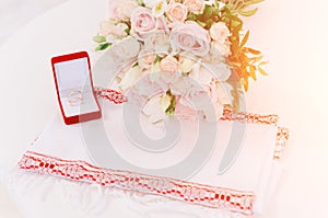 Two gold rings in red box near beautiful creame roses on white background