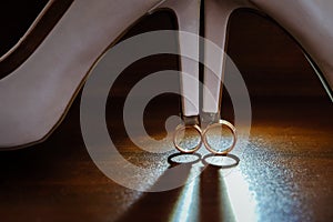 Two gold rings with a white Shoe of the bride on dark background