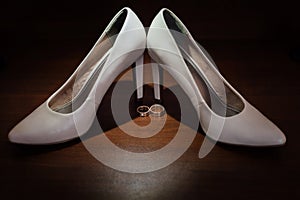 Two gold rings with a white Shoe of the bride on dark background