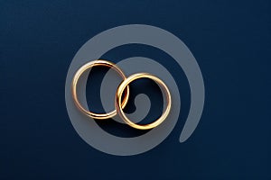 Two gold wedding bands on a dark blue background