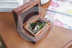 Two gold wedding rings in a beautiful wooden casket with green moss. Wedding accessories. Bride morning