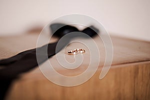 Two gold wedding rings and black tie, groom morning groom, wedding accessories on a brown background