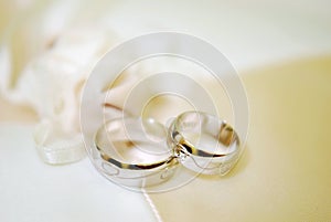 Two gold wedding rings on white lace pad