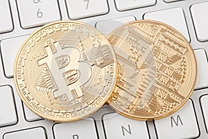 Two golden bitcoin front and back on computer keyboard