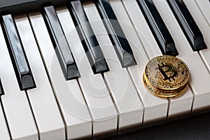 Two golden bitcoins on the keyboards of the piano