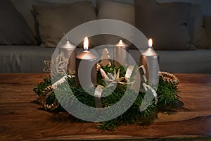 Two golden candles are lit for the second Sunday on an Advent wreath wth natural Christmas decoration on a wooden coffee table,