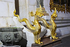 Two golden half naga half lion statues is located on the stairway to the Thai temple