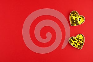 Two golden hearts with confetti on red background for Valentines day. Space for text. Web banner or greeting card