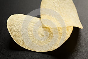 Two golden potato chips on the black, selective focus, close-up