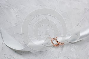 Two golden rings and white satin ribbon wedding decor