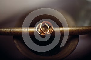 Two golden wedding rings closeup, macro photo of a couple of luxury golden engagement rings on bronze metal background, wedding