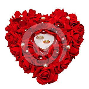 Two Golden wedding rings on a decorative pillow of red roses