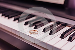 Two golden wedding rings on piano keys