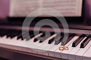 Two golden wedding rings on piano keys