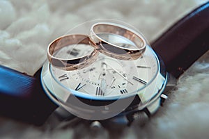 Two golden wedding rings on watch with brown strap