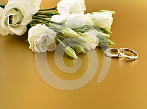 Two golden wedding rings with white flowers on a gold background stock images