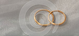 Two golden wedding rings on white silver background, copy space