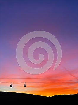 Two Gondola Cabins against Backdrop of Sunrise