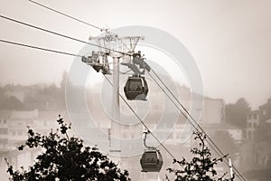 Two gondolas of the Vilanova de Gaia cable car suspended on hanging steel cables descending and ascending under a cloudy white sky photo
