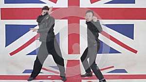 Two good-looking guys in black leather motorcycle jackets synchronically dance.