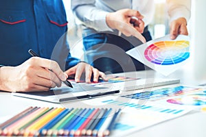 Two Graphic designer drawing on graphics tablet and color palette guide at workplace