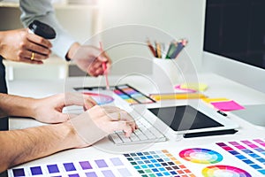 Two Graphic designer drawing on graphics tablet and color palette guide at workplace
