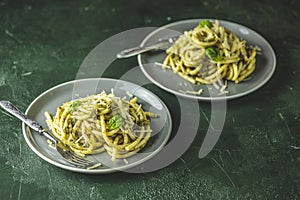 Two gray dishes of spaghetti pasta bucatini with pesto sauce and parmesan. Italian traditional perciatelli pasta by genovese pesto