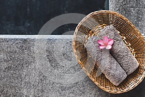 Two gray hand towels in wicker basket on poolside in hotel spa