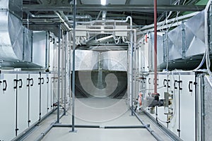 Two gray industrial air handling units in the ventilation plant room with big size ductworks and pipelines photo