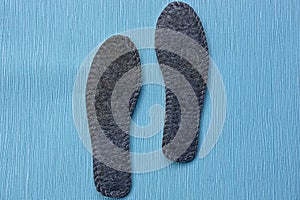 Two gray insoles for shoes on a blue background